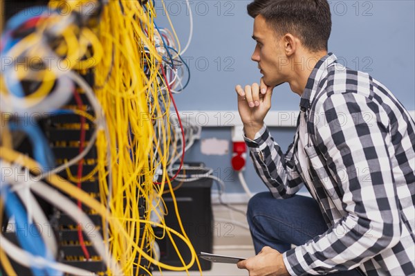 Young network engineer looking wires