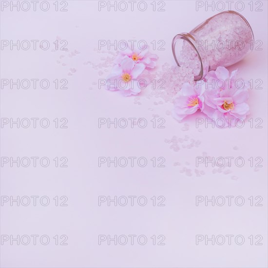 Artificial flowers spilled salt from jar pink background
