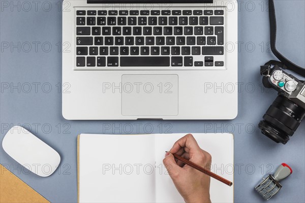 Person writing notebook table with laptop