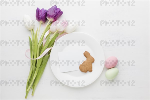 Flat lay bouquet tulips with plate colorful easter eggs