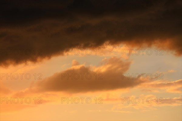 Cloudy sky at sunset. The sky is visible through a gap in the clouds. The image conveys a mood of an impending storm or bad weather