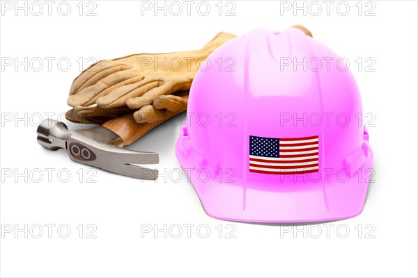 Pink hardhat with an american flag decal on the front with hammer and gloves isolated on white background