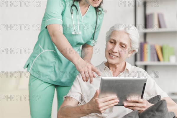 Nurse showing something senior female patient digital tablet