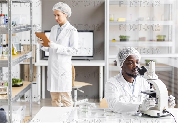 Female male researchers biotechnology laboratory with microscope tablet