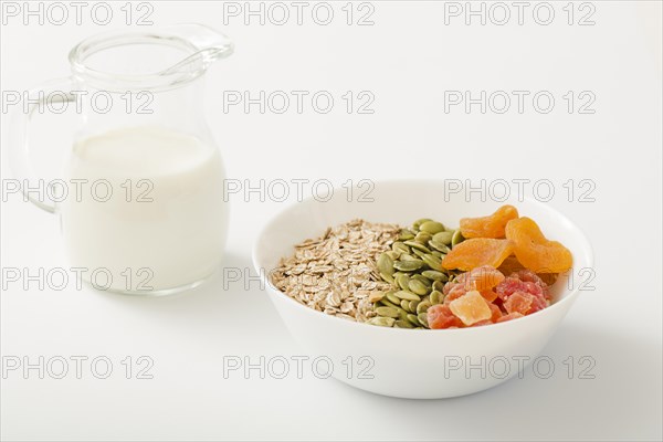Milk with healthy bowl muesli pumpkin seeds dry fruits white bowl white background