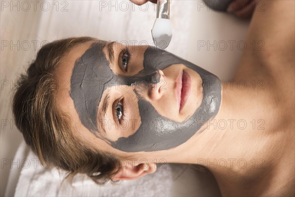 Beautiful young woman applying face mask her face