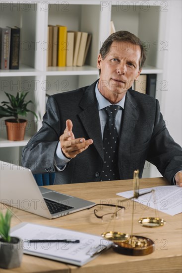 Mature lawyer sitting courtroom gesturing