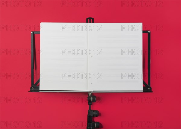 Music stand with blank white musical page red backdrop