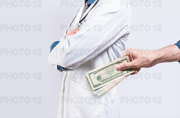 Hand of person bribing doctor. Hands putting money in doctor pocket