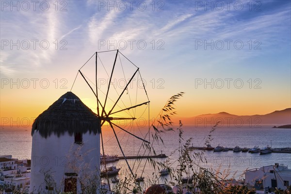 Famous traditional white windmill overlook civil port and harbor of Mykonos