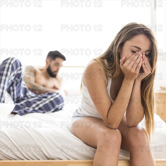 Upset woman sitting bed front her husband