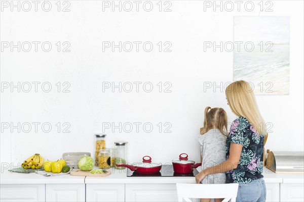 Rear view woman with her daughter kitchen