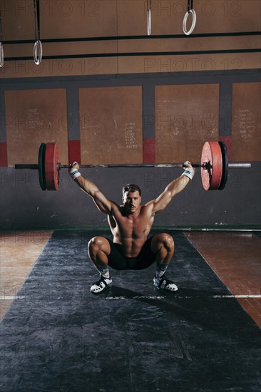 Gym concept with strong man lifting barbell
