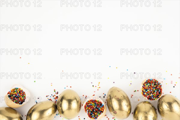 Eggshells with sprinkles near golden eggs