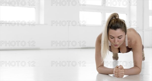 Front view blonde woman doing plank