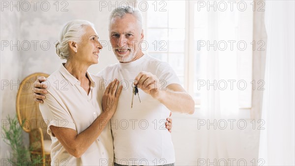 Elderly woman looking her husband showing house key home