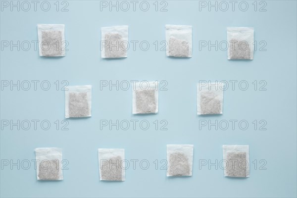 Overhead view teabags arranged against blue background