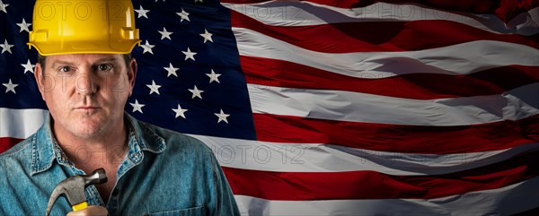 Male contractor wearing blank yellow hardhat over waving american flag background banner