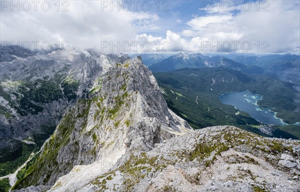 View from the summit of the Waxenstein over the rocky and narrow ridge of the Waxenstein ridge to the Eibsee lake and Hoellental