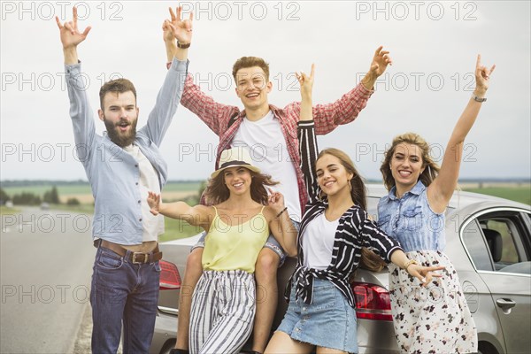 Group friends standing front car raising hands gesturing