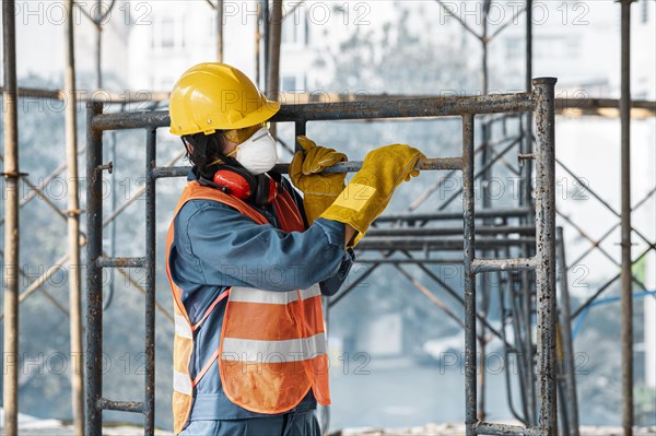 Portrait man with safety equipment side view carrying ladder