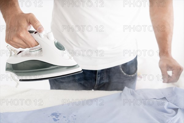 Man steaming clothes with clothing iron