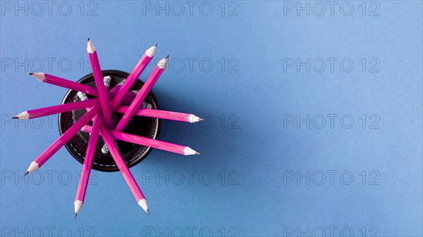 Pink pencils holder against blue background