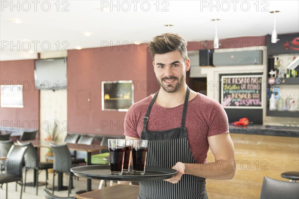 Smiling young man serving glasses drinks restaurant