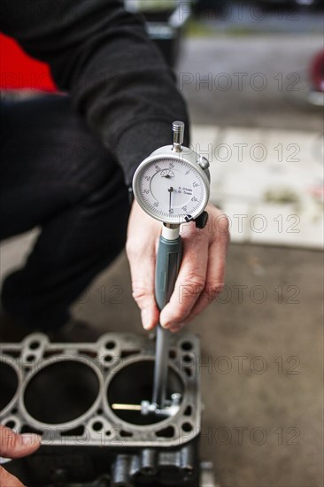 A motor vehicle assessor inspects a cylinder head of a car engine