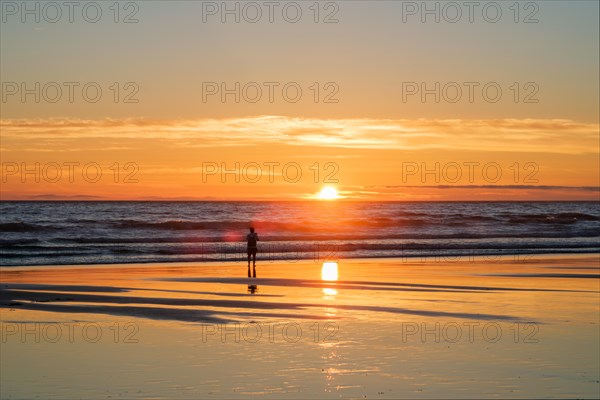 Atlantic ocean sunset with photographer silhouette taking images of surging waves at Fonte da Telha beach