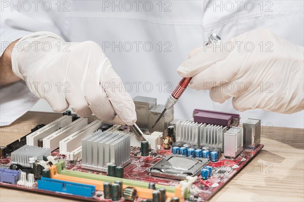 Technician wearing gloves working computer motherboard