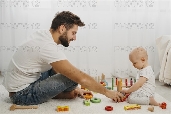Father teaching baby play with toys home