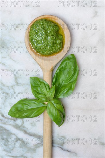 Pesto in wooden spoon and basil