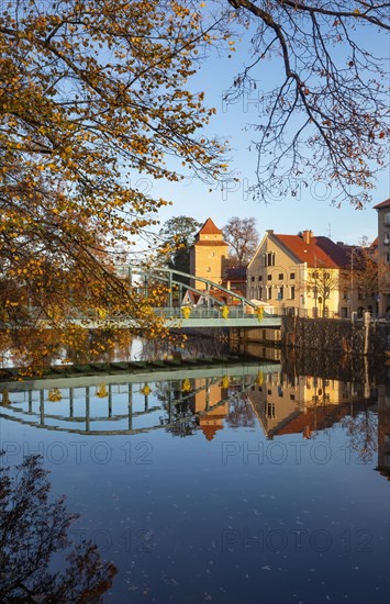 Autumnal coloured trees with iron bridge over the river Maltsch with the city wall of the historical old town of Ceske Budejovice