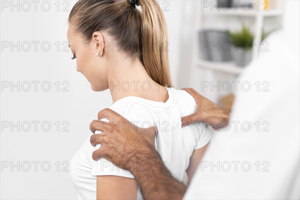 Male physiotherapist checking woman s back shoulders