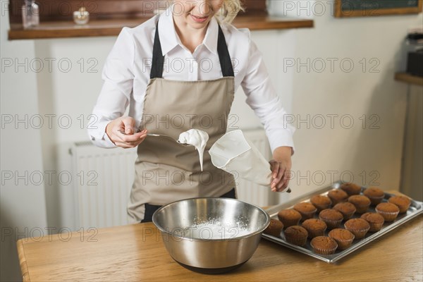 Close up young woman putting white cream pastry bag