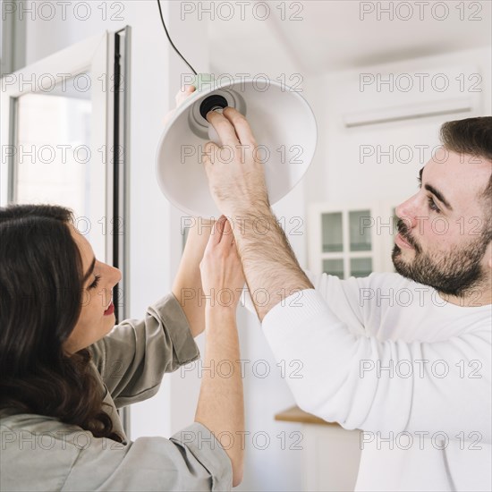 Couple changing light bulb