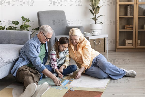 Full shot grandparents kid doing puzzle