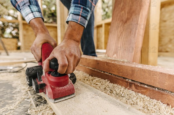 Construction worker sanding down wood piece