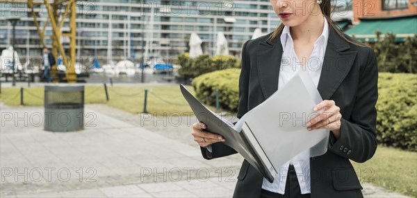 Close up young businesswoman reading folder outdoors