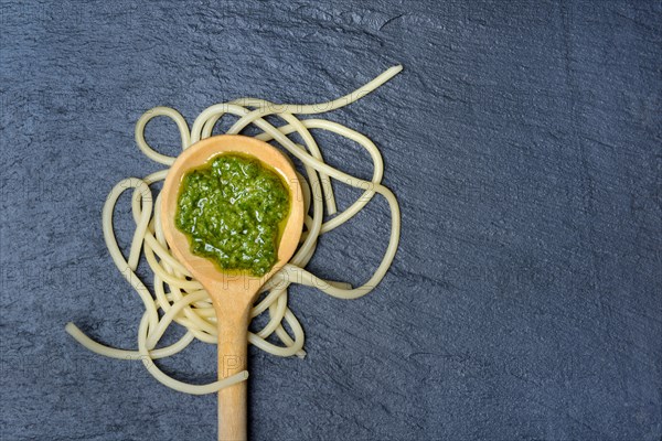 Pesto in cooking spoon and spaghetti