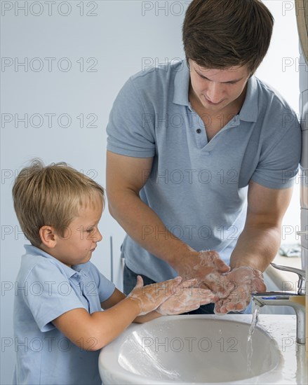 Portrait dad teaching son how wash hands