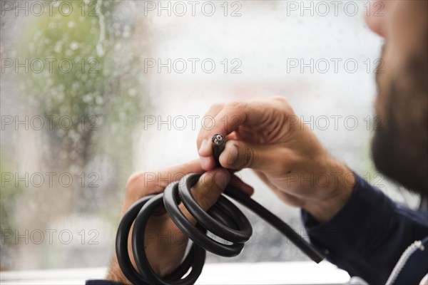 Close up electrician s hand holding black electric cable