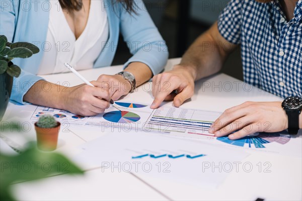 Crop people comparing data chart