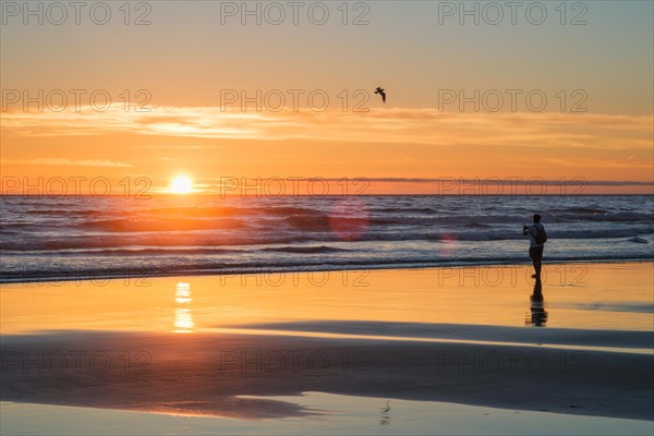 Atlantic ocean sunset with photographer silhouette taking images of surging waves at Fonte da Telha beach