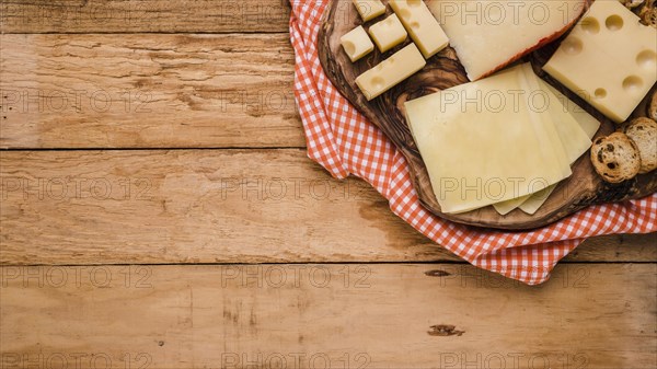 Different types cheeses wooden coaster with table cloth bench