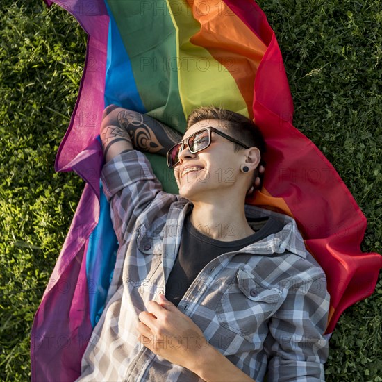 Cheerful young person lying lgbt flag park