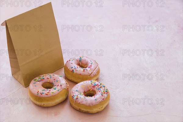 Three delicious donuts with parcel pink background