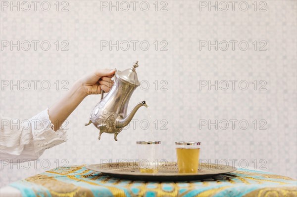 Hand pouring tea into glass
