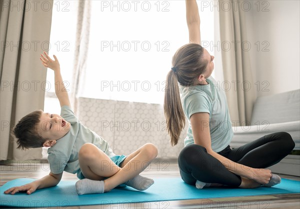 Happy young boy exercising with mom